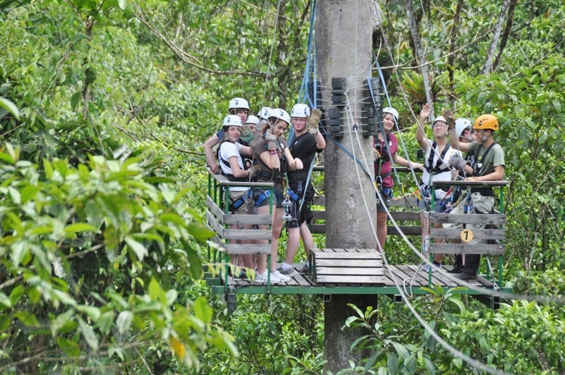 Team members zip-lining through the jungle canopy