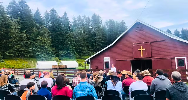 A worship gathering outside a barn chapel