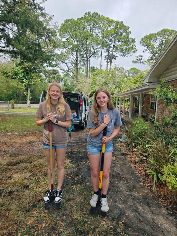 Two students holding shovels during a service project