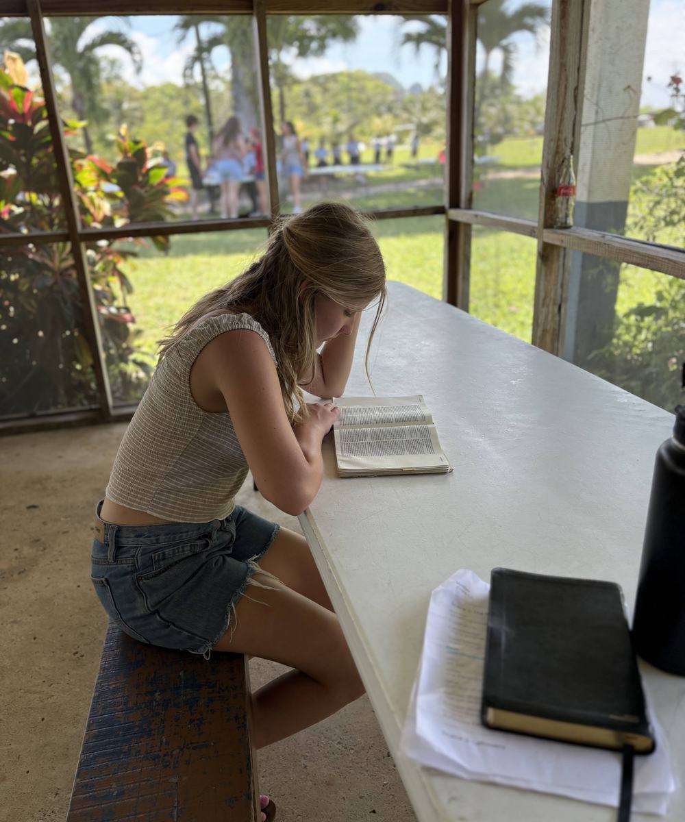 A student reading her Bible at a table during a mission trip