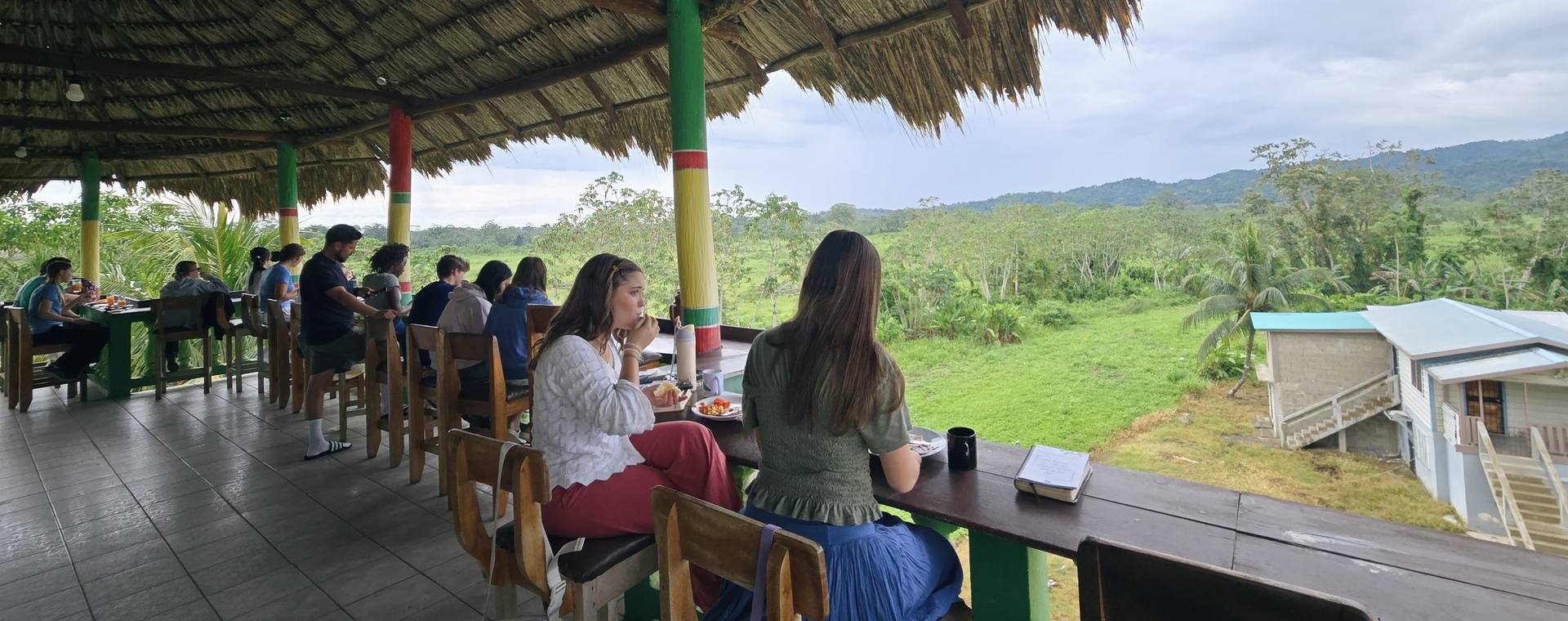 A GO Serve team sharing a meal at a long table overlooking the Belize countryside