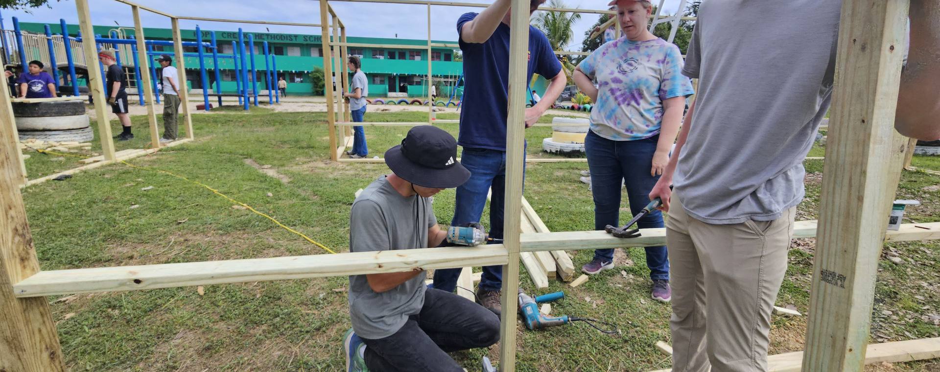 A student and a leader building a wooden frame together