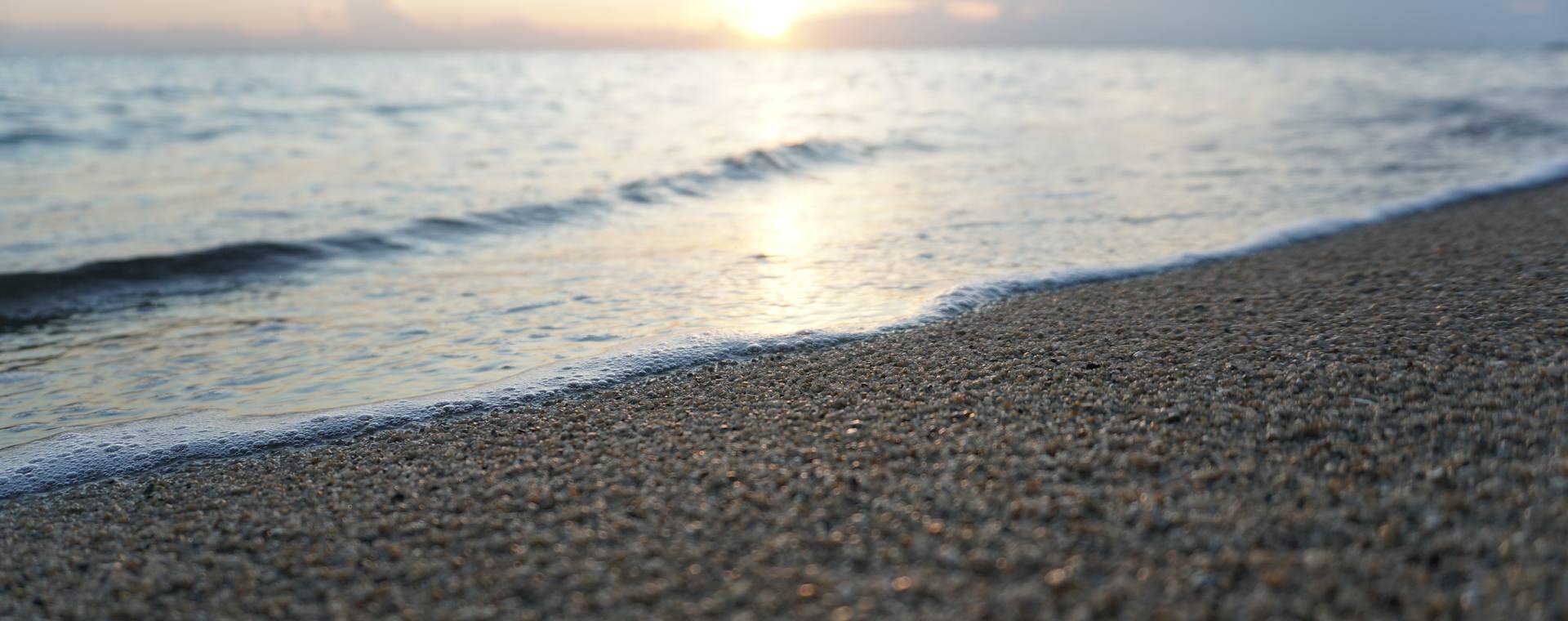 Sunrise glowing over calm water at the shore