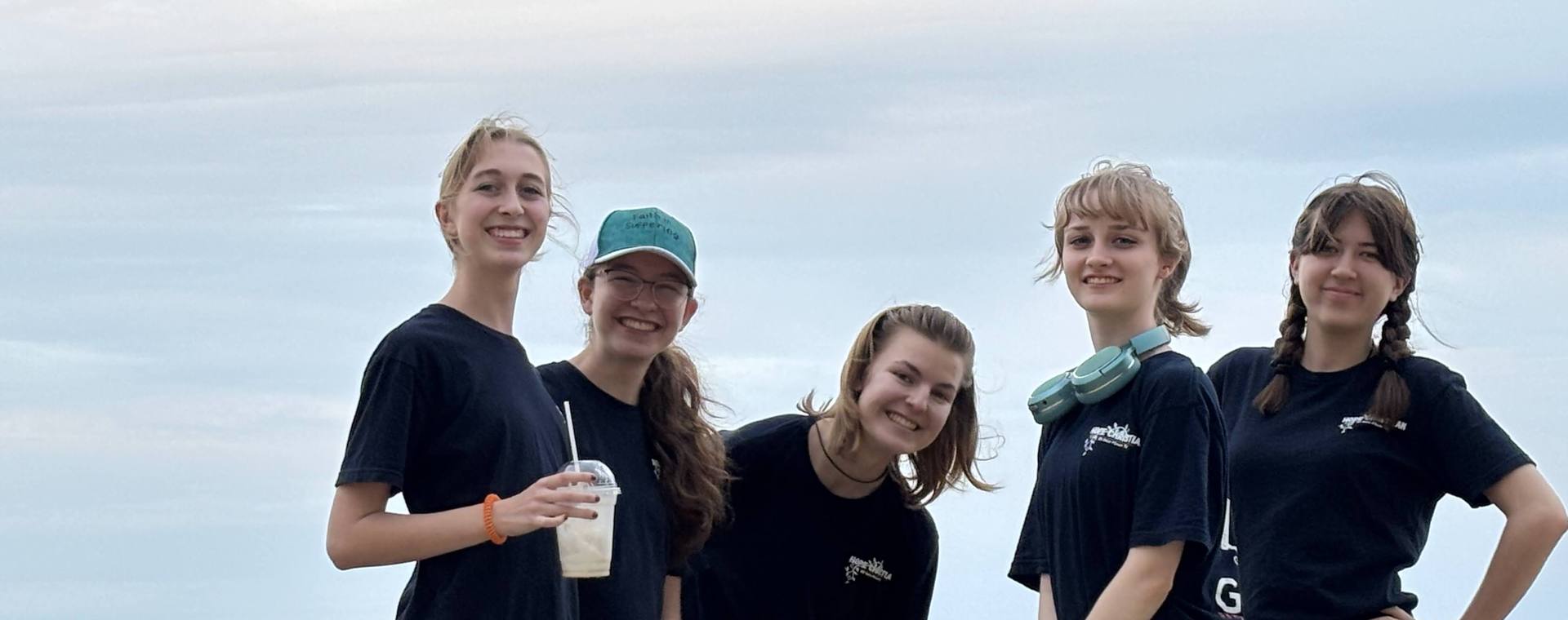 Five smiling GO Serve students standing together at the water's edge