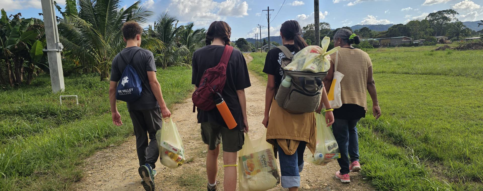 Students and a community member walking together along a village path