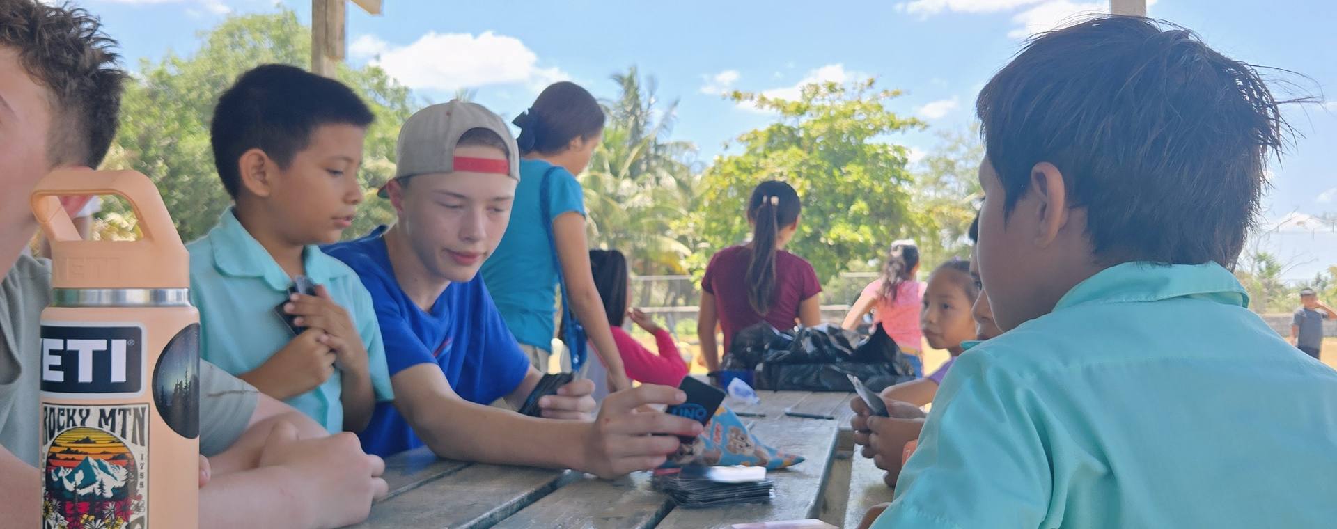 GO Serve students playing cards with local students at a picnic table