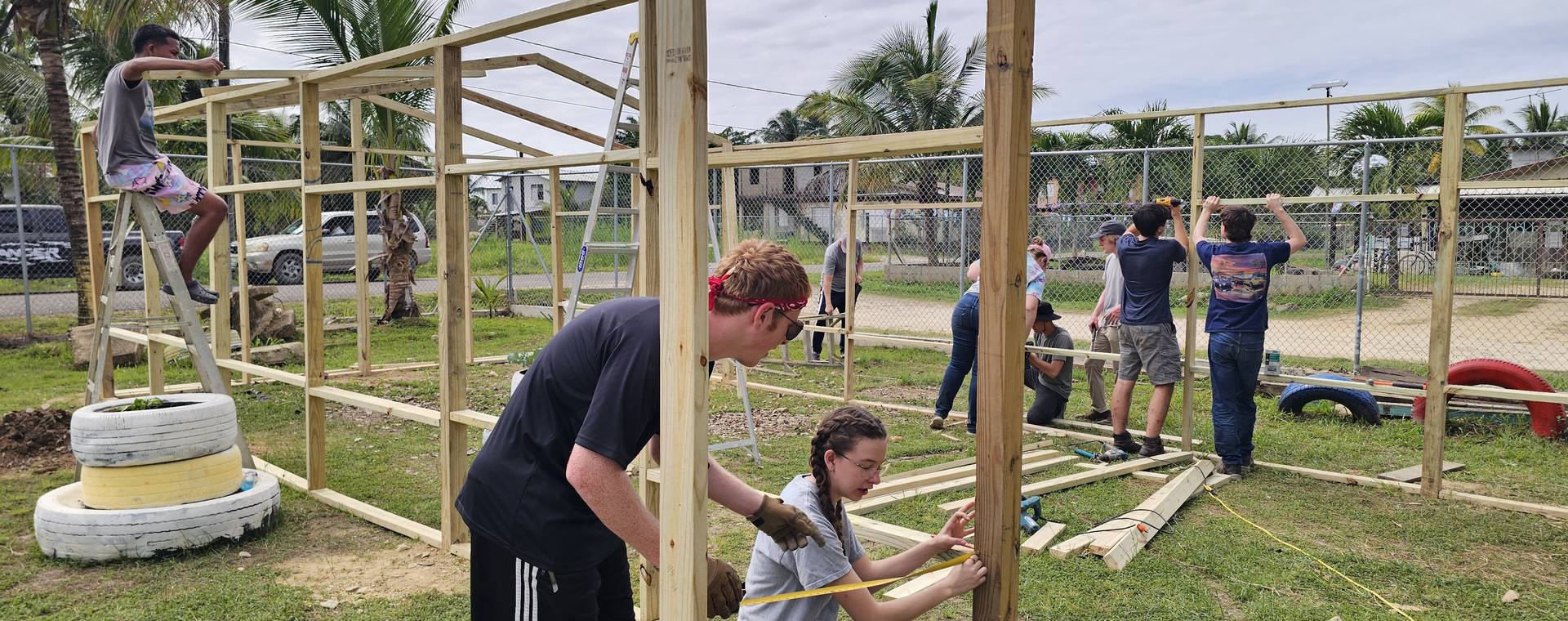 Students and a leader building a wooden frame together at a partner school