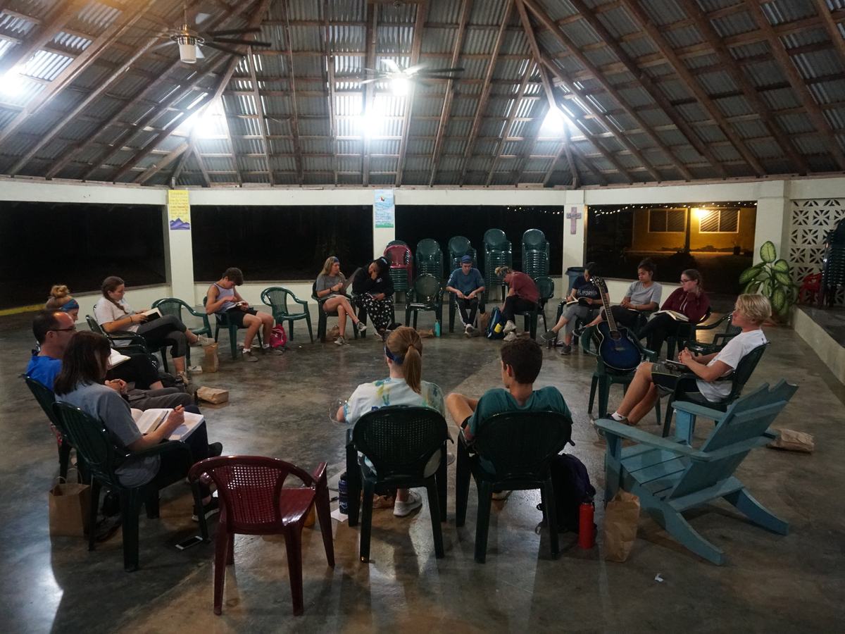 A team gathered in a circle of chairs for an evening conversation