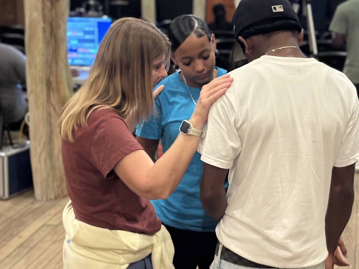 A team member praying with two friends