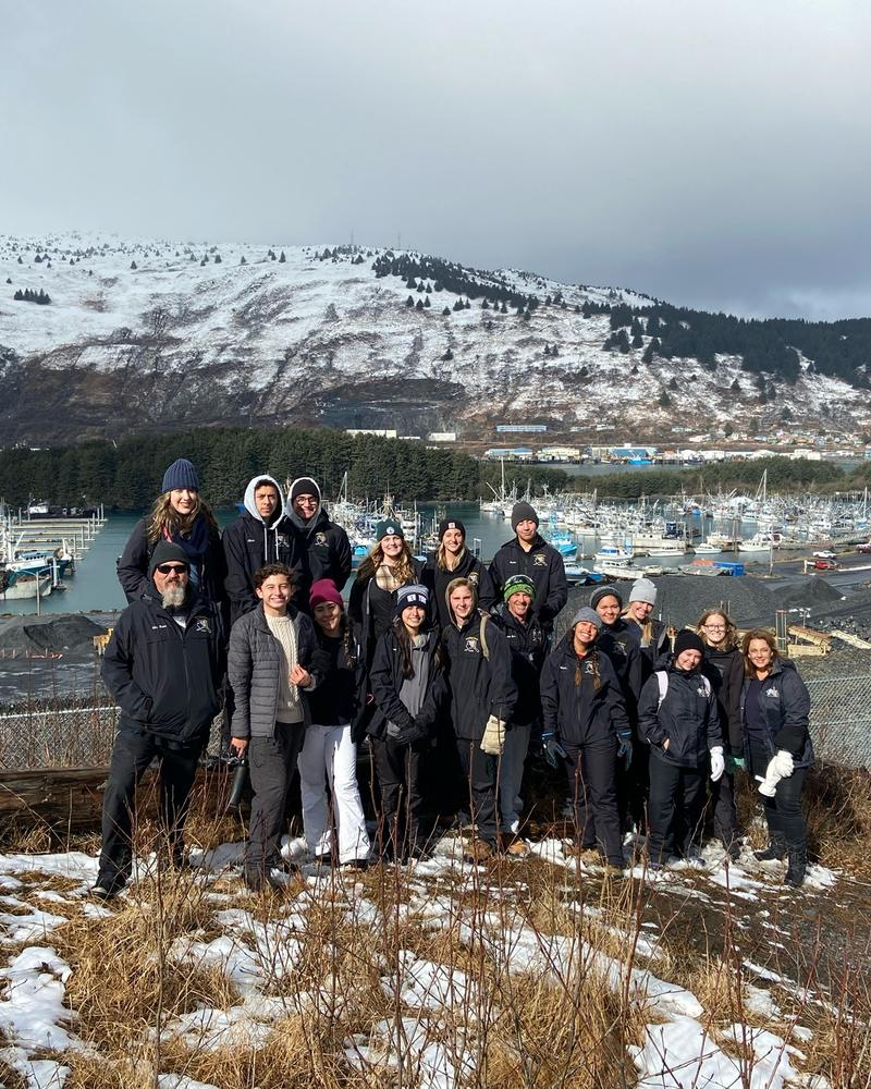 A GO Serve team gathered above a snowy harbor and mountains in Kodiak, Alaska
