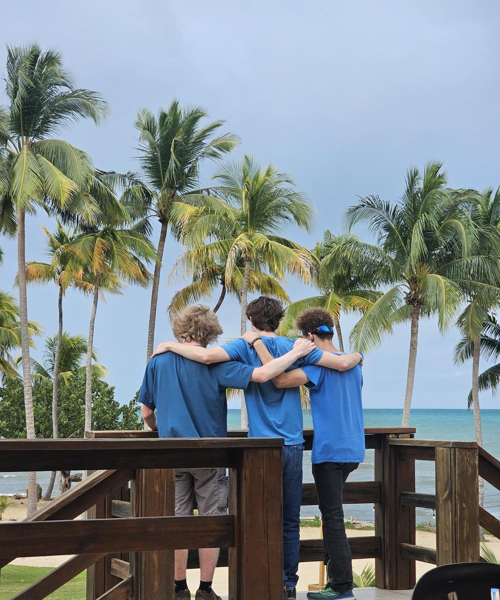 Three friends standing arm in arm looking out over the ocean