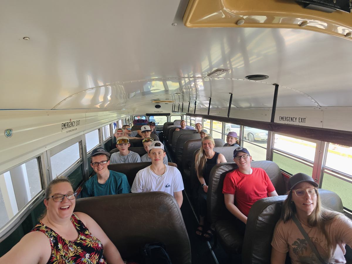Trip leaders and parents smiling together on a bus
