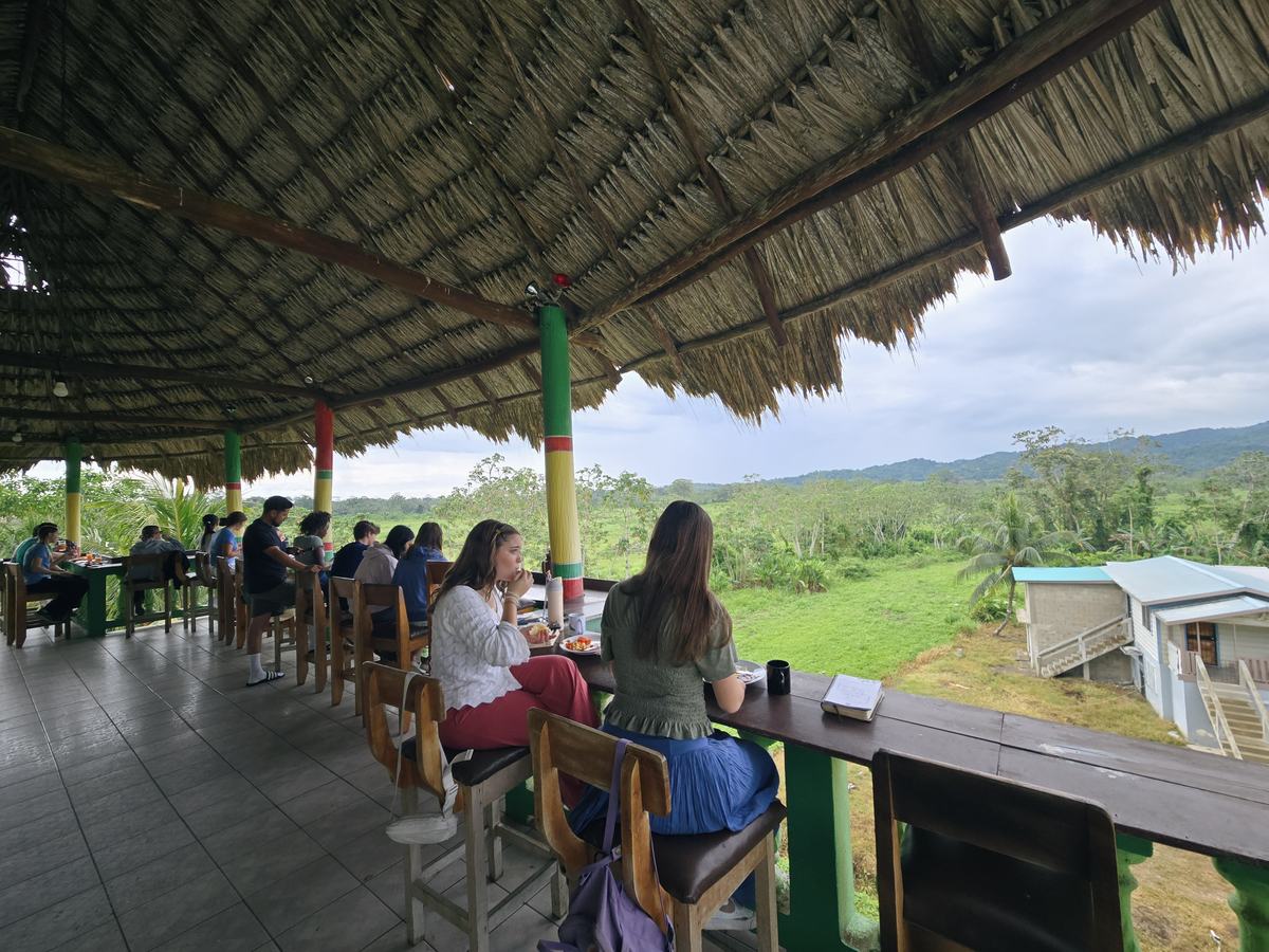 A GO Serve team sharing a meal at a long table overlooking the Belize countryside